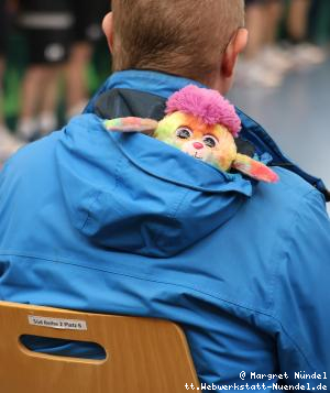Bunte Puppe in der Kapuze eines Zuschauers